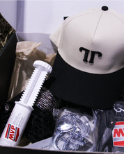 Open Saddle Society box with a cream and black snapback cap, supplement syringe, and black hay net